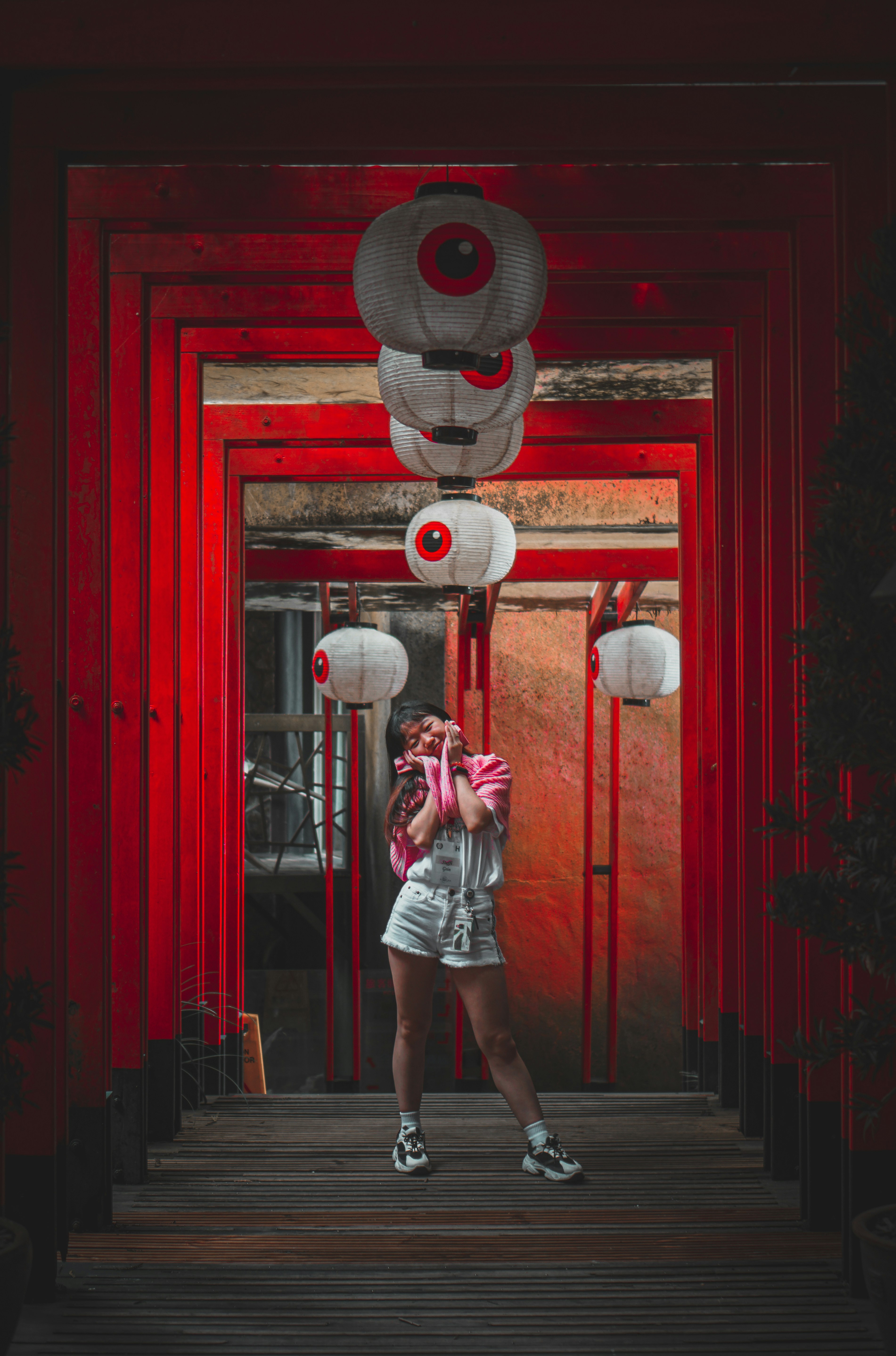 woman in white shirt and black shorts standing beside red door